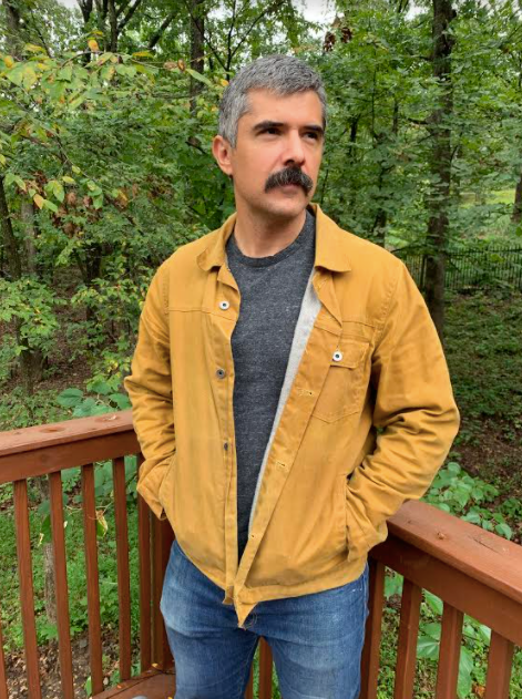 man wearing flint and tinder trucker jacket with wooded background.