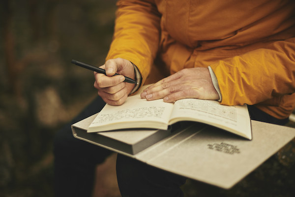 man journaling outdoors to help focus