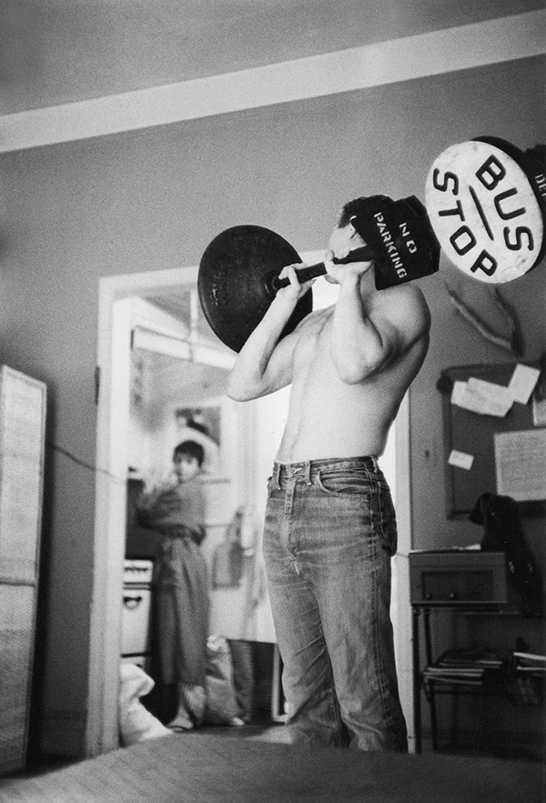 Steve McQueen shoulder pressing a bus stop sign