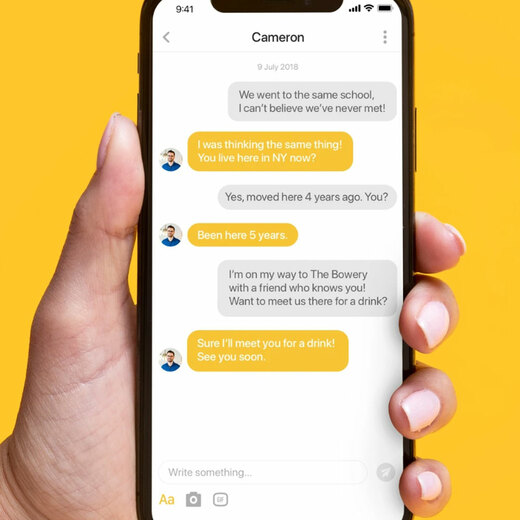 Bumble message screen open on smartphone, hand holding smartphone and set on yellow background